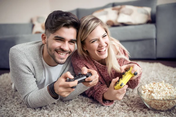 笑顔のカップルが彼らのリビング ルームでビデオ ゲームをプレイ — ストック写真