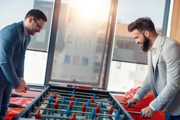 Modern ofis masa futbolu oynayan gülümseyen iş arkadaşları.