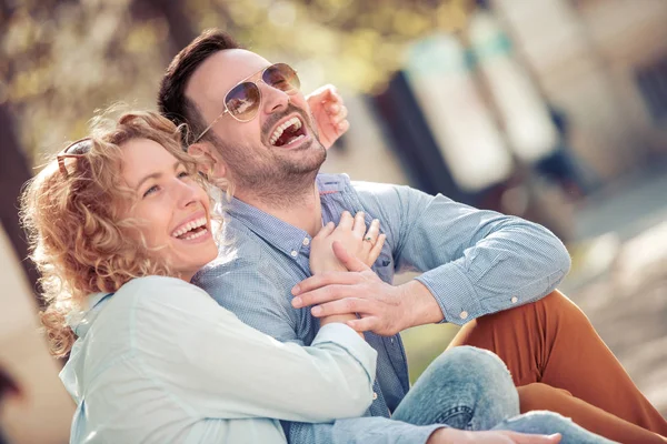 Konuşmak ve açık havada birlikte oturan gülümseyen güzel genç çift.