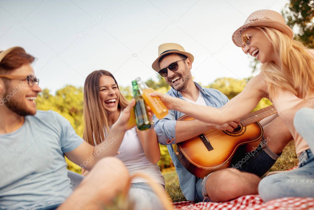 Happy young friends having picnic in the country. They are all happy, having fun, smiling and enjoying together.