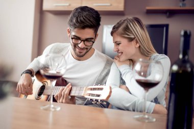 Akustik gitar ve kırmızı şarap ile birlikte evde istirahat mutlu genç çift.