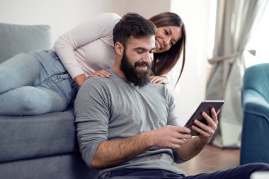 Evde bir tablet ile rahatlatıcı mutlu genç çift.