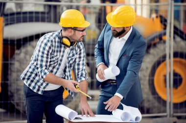 İki oluşturucular inşaat sahasında yeni planı ile mühendis.