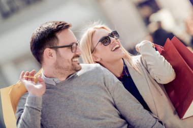 Fotoğrafta şehirde alışveriş yapan genç bir çift görülüyor..