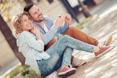 Konuşmak ve açık havada birlikte oturan gülümseyen güzel genç çift.