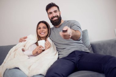 Televizyon izlerken mutlu çift kahve içip patlamış mısır kanepede - Aile, eğlence, eğlenceli ve mutluluk kavramı.
