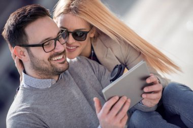 Mutlu çift veya sarılma ve sokağın ortasında bir tablet paylaşımı arkadaşlar.