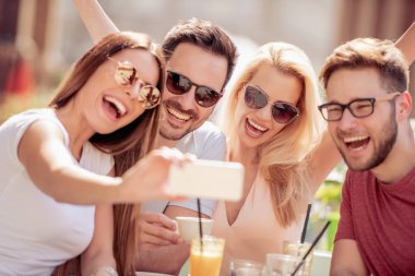 Bir kafede kahve zevk dört gülen arkadaş. Onlar birlikte iyi vakit geçiriyor.