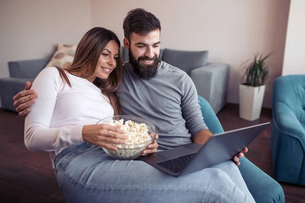 Bir erkek ve bir dizüstü bilgisayar ile bir kanepede oturan kadın portresi.