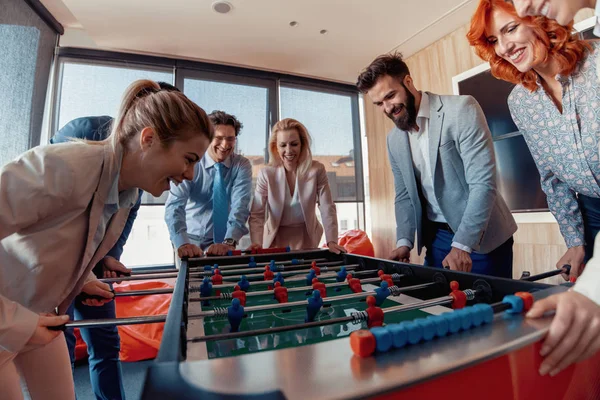 Modern ofis masa futbolu oynayan gülümseyen iş arkadaşları.