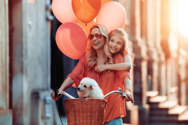 Güzel anne ve şehirde, eğleniyor kızı Bisiklete binmek.