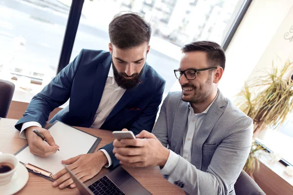 İki emin işadamı ile bir gülümseme onay iş ofis telefon.