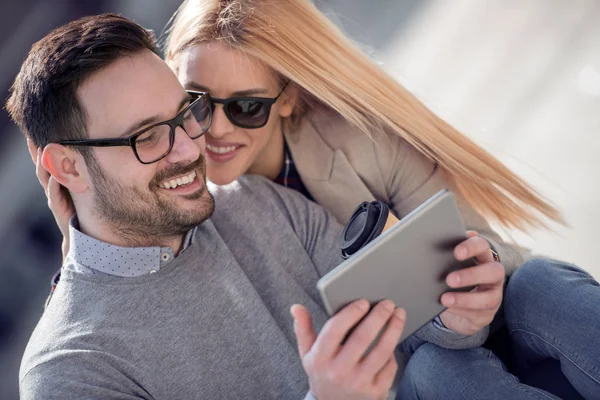Mutlu çift veya sarılma ve sokağın ortasında bir tablet paylaşımı arkadaşlar.