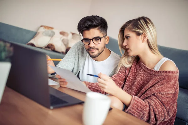 Dizüstü bilgisayar kullanarak ve kendi mali arıyorum genç çiftin fotoğrafı.
