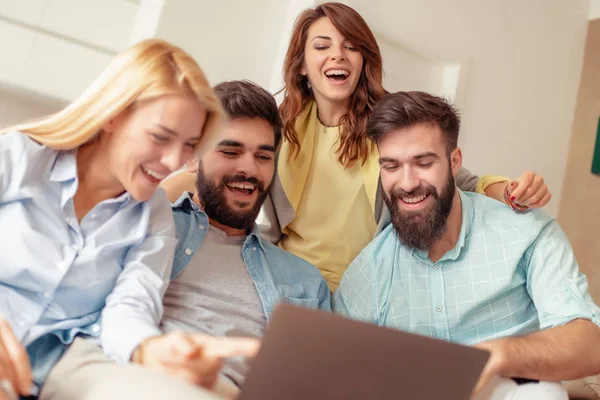 Birlikte kanepede oturan ve laptop komik video izlerken arkadaşlar.