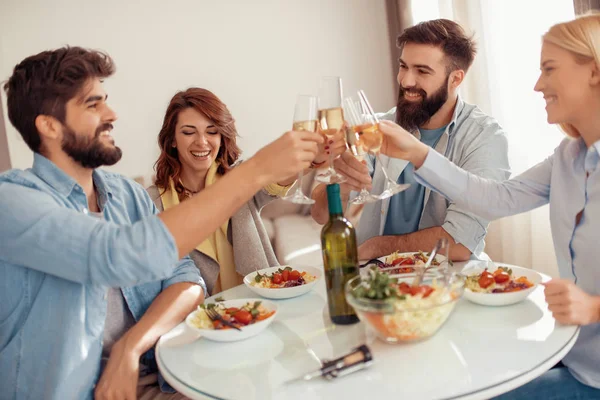 Group of happy people with glasses, talking and eating healthy meals at party dinner.