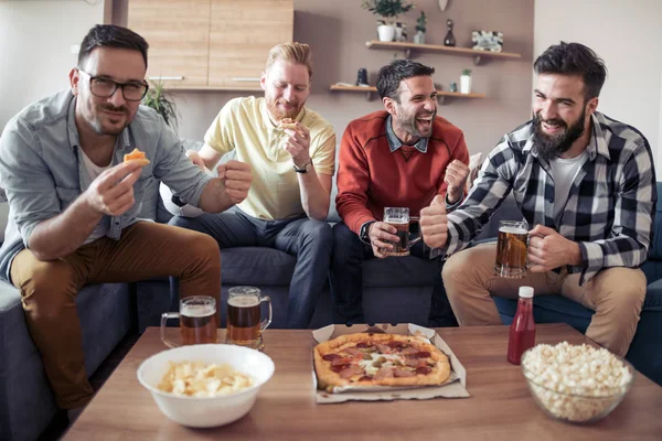 Bira, patlamış mısır ve evde spor izliyor fiş ile mutlu erkek arkadaşlar.