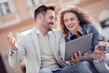 Açık havada eğleniyor ve gülümseyerek, laptop arıyorum mutlu genç çift.