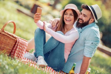 Mutlu çift birbirlerine gülümseyen güneşli bir günde bir piknik üzerinde. İnsanlar, sevgi, mutluluk ve doğa kavramı.