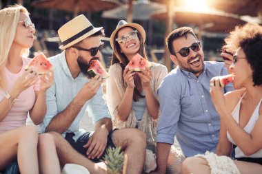 Neşeli grup plajda eğlenmek ve karpuz yeme arkadaşıyla