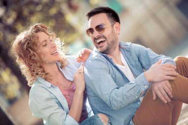 Konuşmak ve açık havada birlikte oturan gülümseyen güzel genç çift.