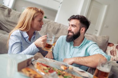 Evde harika zamandı, pizza yemek ve şarap içmek genç çift.