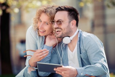 Tablet kullanma ve sokakta müzik dinlemek genç çift portresi.