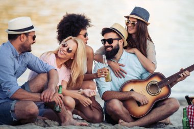 Arkadaşlar eğlenmeye sahilde gitar ile neşeli grup.