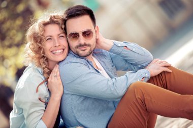 Konuşmak ve açık havada birlikte oturan gülümseyen güzel genç çift.