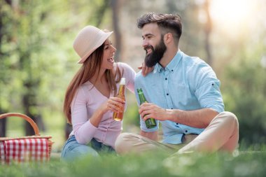 Mutlu çift birbirlerine gülümseyen güneşli bir günde bir piknik üzerinde. İnsanlar, sevgi, mutluluk ve doğa kavramı.