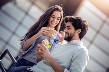 Mutlu bir çift portresi. Onlar gülüyor ve sandviç yeme ve having a büyük zaman.