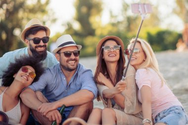 Neşeli grup arkadaşıyla birlikte eğleniyor plaj ve alma selfie.