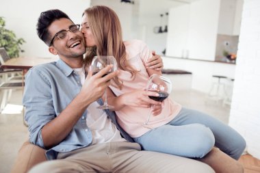 Güzel genç çift bardak kırmızı şarap oturma odasında öpüşme ile.