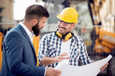 Planı plan inşaat sahasında iki mühendis.