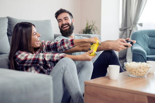 幸せなカップルは 彼らのリビング ルームで一緒に座って コント ローラーを押し ビデオ ゲームをプレイしながら笑って — ストック写真