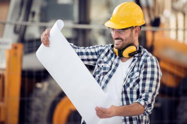 İnşaat alanında, kask ile iş yerinde genç mimar portresi okur proje.