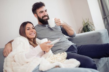 Onların evinde rahatlatıcı, kanepede oturan, bir film seyrederken ve patlamış mısır yemek Genç Çift. 