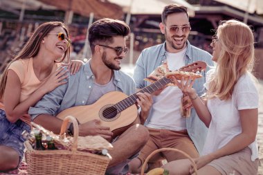 Arkadaşlar eğlenmeye sahilde gitar ile neşeli grup.