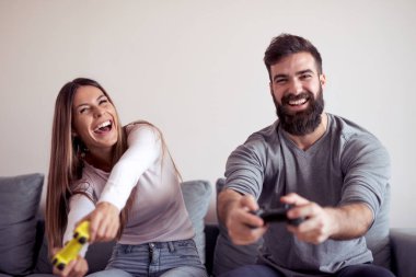 Mutlu çift birlikte onların oturma odasında oturma ve bir video oyunu oynarken gülüyor.