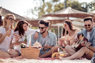 Arkadaşlar eğlenmeye sahilde gitar ile neşeli grup.