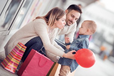 Satılık, tüketim ve aile kavramı - küçük çocuk ve şehirde alışveriş torbaları ile mutlu aile.