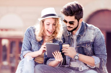 İki genç insanlar tablete arıyorum gülümseyen.