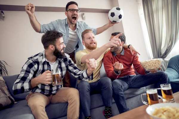 Friendship, sports and entertainment-happy male friends with beer,popcorn and chips watching sports at home.