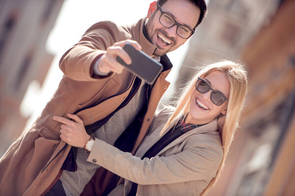 Happy couple of tourists taking selfie in the city.