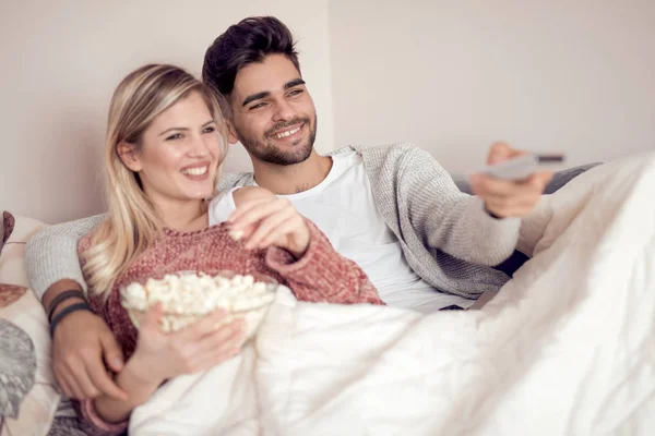 Feliz Pareja Joven Tumbada Sofá Casa Con Palomitas Maíz Viendo — Foto de Stock