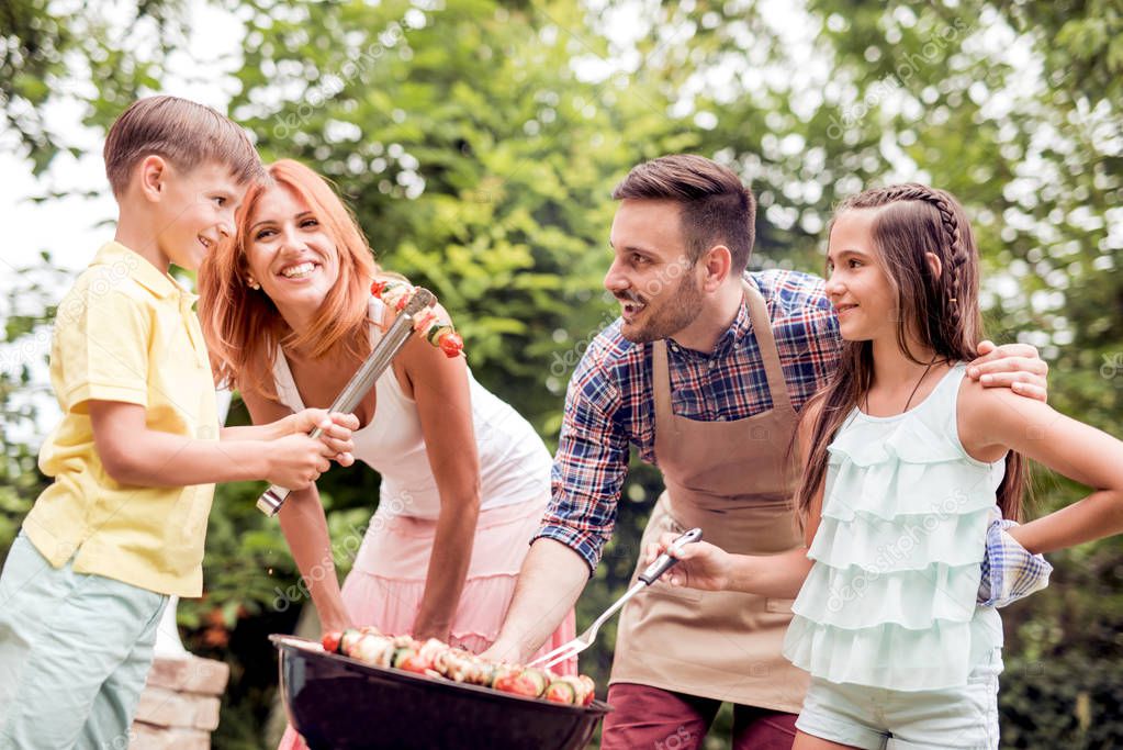 Food, people and family time concept - man cooking meat on barbecue grill at summer party.