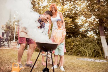 Mutlu genç baba kızı, eşi ve oğlu ile barbekü güneşli bir günde yapma.