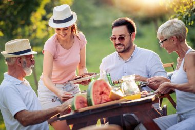 Mutlu büyük bir aile yaz aylarında bir piknik masa etrafında öğle süre having fun.