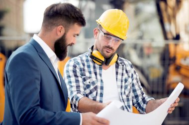 İki oluşturucular inşaat sahasında planı ile mühendis.