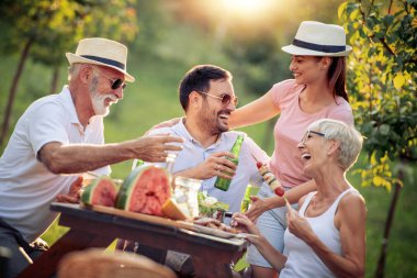 Mutlu büyük bir aile yaz aylarında bir piknik masa etrafında öğle süre having fun.